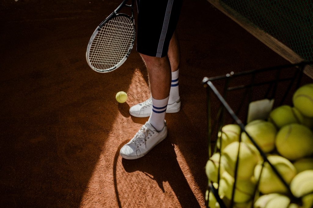Joueur de tennis, jouant sur un terrain en terre battue, raquette en main et balle