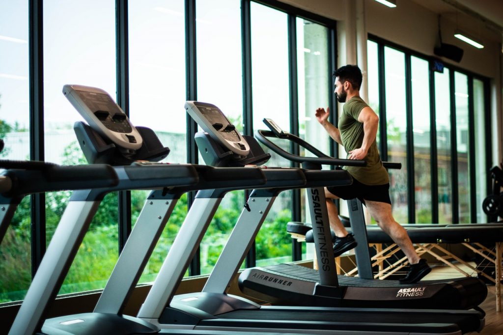 Homme courant sur un tapis de course en salle de sport