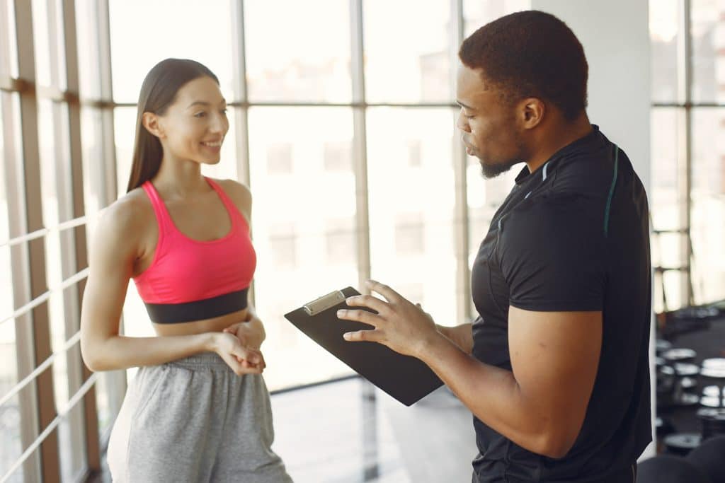Jeune femme discutant avec un coach sportif pour sa préparation sportif